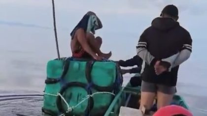 Korban kecelakaan perahu duduk di atas rakitan jeriken mengapung di laut, didampingi tim penyelamat yang menggunakan perahu