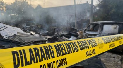 Garis polisi di lokasi kebakaran Pasar Panjang Kendari dengan puing-puing kios dan kendaraan yang hangus terbakar.