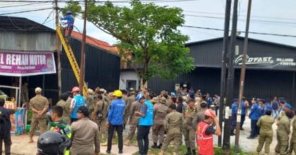 Petugas PLN memutus aliran listrik di bangunan usaha Dfast Biliar, Jalan Martandu, Kota Kendari, disaksikan aparat Satpol PP dan kerumunan warga saat penertiban pelanggaran tata ruang.